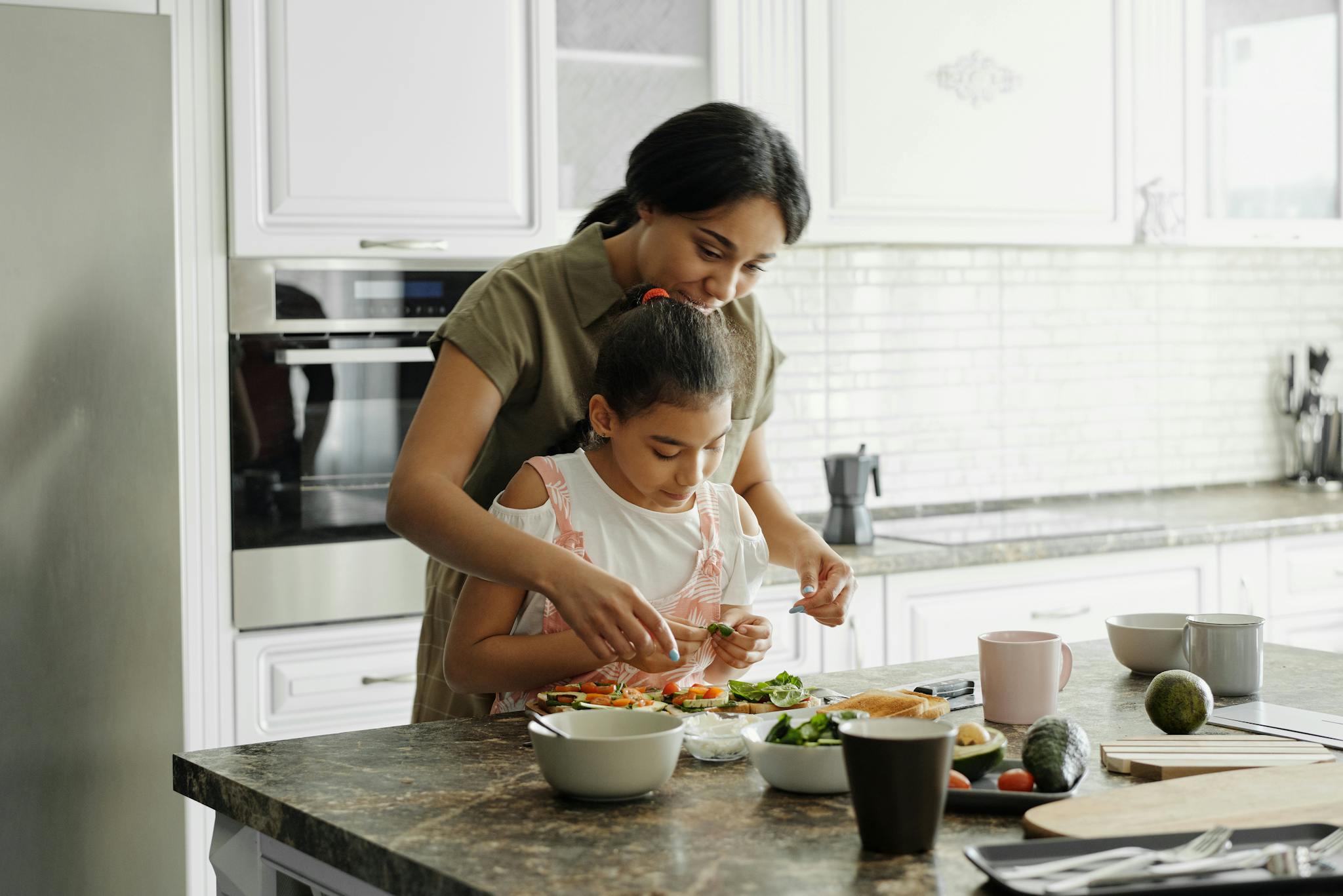 Mother and Daughter Preparing Food In Kitchen